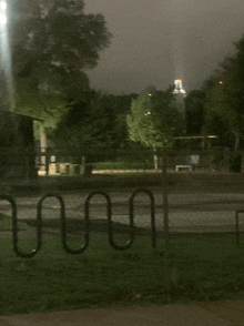 a fence is surrounded by a swirl shaped bike rack at night