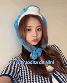 a woman wearing a blue hat with the words soy todita de nini written below her