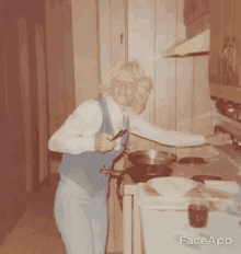 a woman in a blue vest is cooking in a kitchen with faceapp written on the bottom right