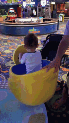 a little boy is sitting in a yellow and blue bowl with a sign in the background that says rule o'neillson