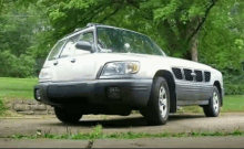 a white car is parked on the side of the road in front of trees