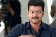 a man with a mustache is wearing a blue shirt that says vimal on the bottom