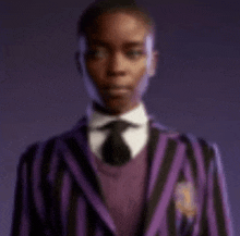 a blurry picture of a man wearing a purple and black striped jacket and tie .