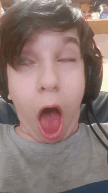 a young boy wearing headphones makes a funny face with his mouth open