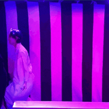 a person is standing in front of a striped wall with purple lights