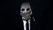 a man in a suit and tie has a scarecrow mask on