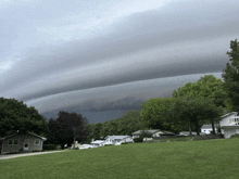 a cloudy sky over a residential area with houses and trees in the foreground