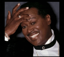 a man in a tuxedo with a ring on his finger covering his face