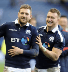 two men wearing scotland jerseys are hugging and smiling