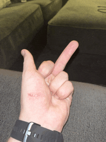 a person 's hand with a black watch on their wrist is giving the middle finger