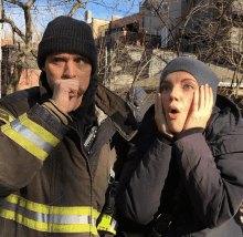 a man in a fireman 's jacket and a woman in a gray hat are posing for a picture