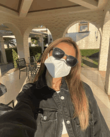 a woman wearing a mask and sunglasses is taking a selfie