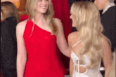 two women in red and white dresses are standing next to each other and talking to each other .