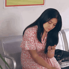 a woman in a pink dress is sitting in a chair