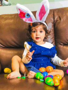 a little girl wearing bunny ears sitting on a couch