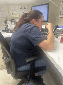 a woman sits at a desk with a can of coca cola on the table