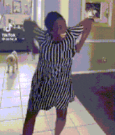 a woman in a striped dress is dancing in front of a dog