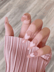 a close up of a woman 's nails with pink hearts