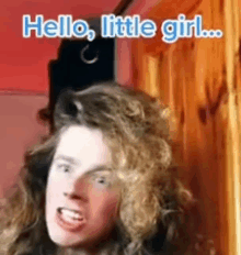 a man with long curly hair is making a funny face and says `` hello little girl '' .