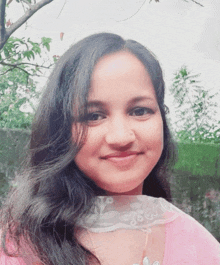 a woman wearing a pink top with a white lace collar is smiling