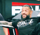 a man with a beard is sitting in front of a sign that says p on it
