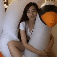 a woman is sitting on a couch holding a large inflatable swan .