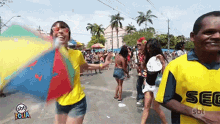 a man in a yellow shirt that says sec is standing next to a woman holding a colorful umbrella .