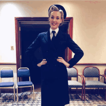 a woman in a suit and tie stands in a hallway with chairs