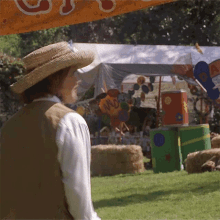 a man in a straw hat stands in front of a tent with a sign that says nc on it