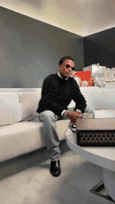 a man is sitting on a couch with his legs crossed