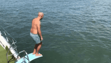 a man is jumping into a body of water from a diving board .