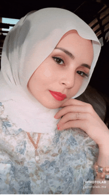 a woman wearing a white hijab and red lipstick is taking a selfie