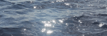 a close up of a body of water with waves and the sun shining on it