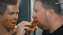two men are eating a donut with hbo on the bottom right