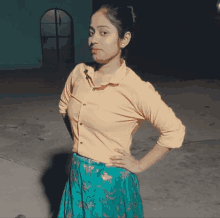 a woman in a yellow shirt and a blue skirt is standing with her hands on her hips