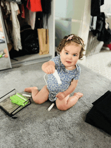 a baby is sitting on the floor playing with a remote control