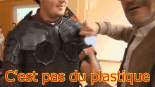 a man in armor is being interviewed by another man and the words c'est pas du plastique are displayed