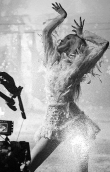 a black and white photo of a woman in a dress made of feathers dancing .