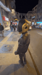 a man wearing a helmet and a leather jacket is standing on a sidewalk