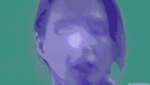 a close up of a man 's face with a purple light shining on it .