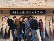 a group of people standing in front of a brick building with a sign that says 943 king 's cross