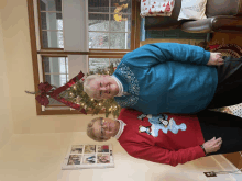 two women wearing ugly christmas sweaters are standing in front of a christmas tree