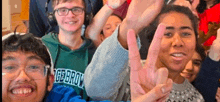 a group of people are posing for a picture and one of them is making a peace sign .