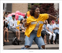 a woman in a yellow jersey with the word house on it is dancing in front of a crowd