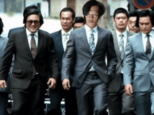 a group of men in suits and ties walking down a street