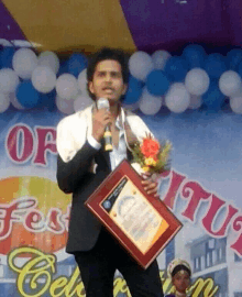 a man in a suit is holding a plaque and a microphone