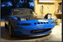 a blue sports car is parked in a garage with its headlights on .