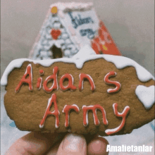 a person holding a cookie that says aidan 's army on it