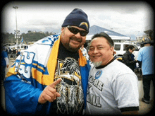 two men are posing for a picture and one of them is wearing a shirt that says ' la ' on it