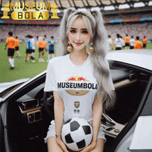 a woman holding a soccer ball wearing a museumbola shirt